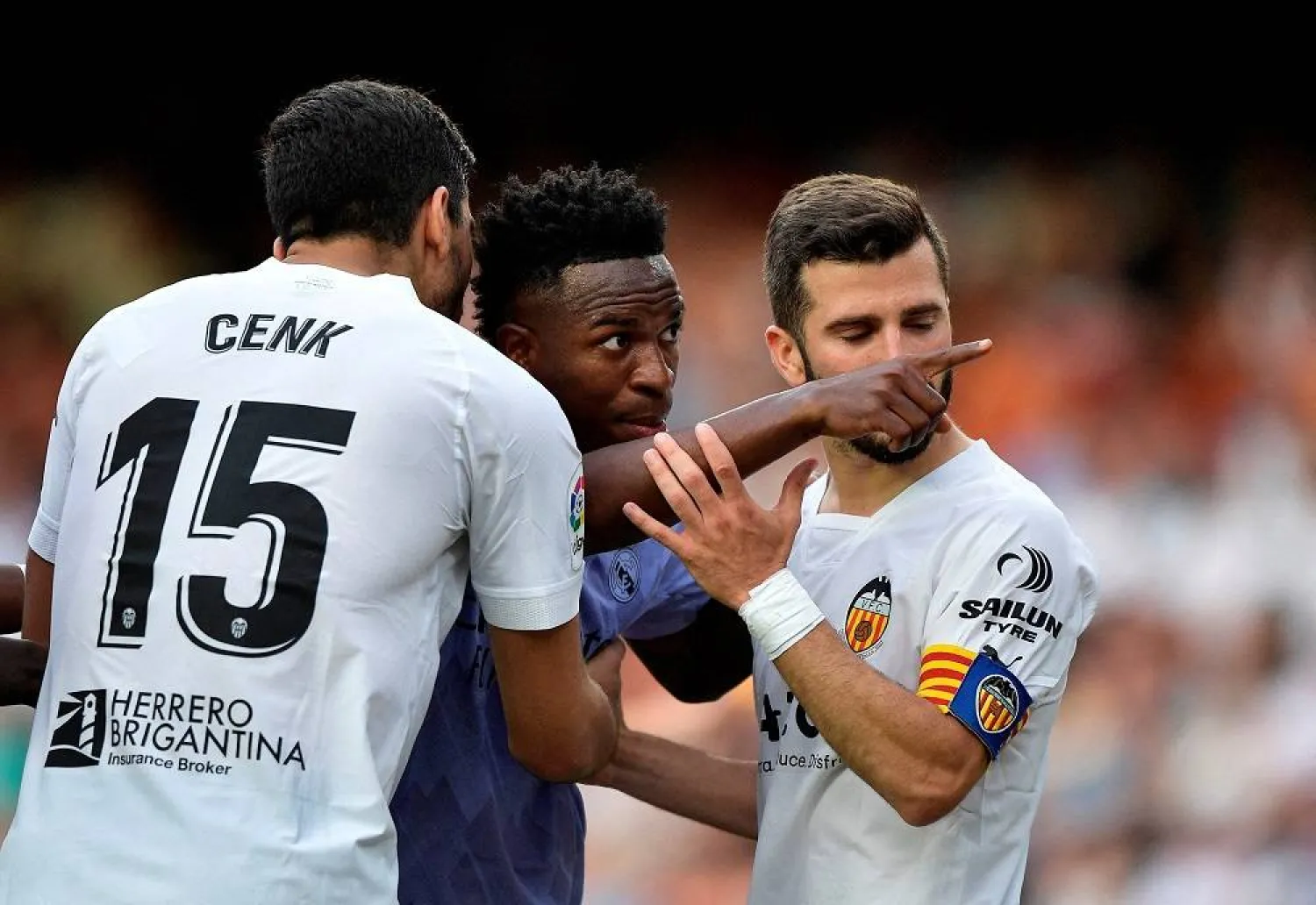 Football - LaLiga - Valencia v Real Madrid - Mestalla, Valencia, Spain - May 21, 2023 Real Madrid's Vinicius Junior gestures towards a fan as Valencia's Jose Gaya and Cenk Ozkacar attempt to restrain him. (Reuters) 