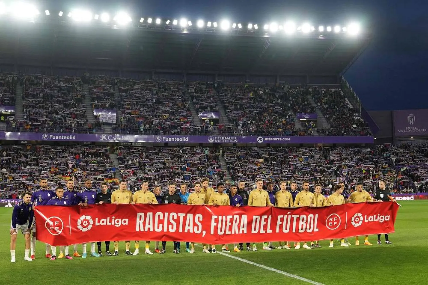 Players and match officials hold a banner reading "Racists, out of football" at half-time during the Spanish league football match between Real Valladolid FC and FC Barcelona at the Jose Zorilla stadium in Valladolid on May 23, 2023. (AFP) 