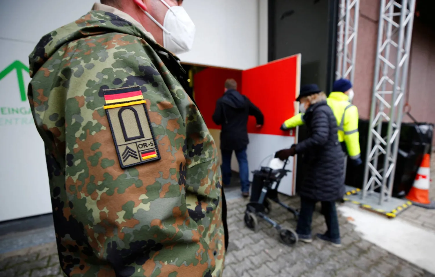 جندي ألماني ينظم طوابير الدخول في أحد مراكز اللقاح المؤقتة بمدينة كولونيا (رويترز)