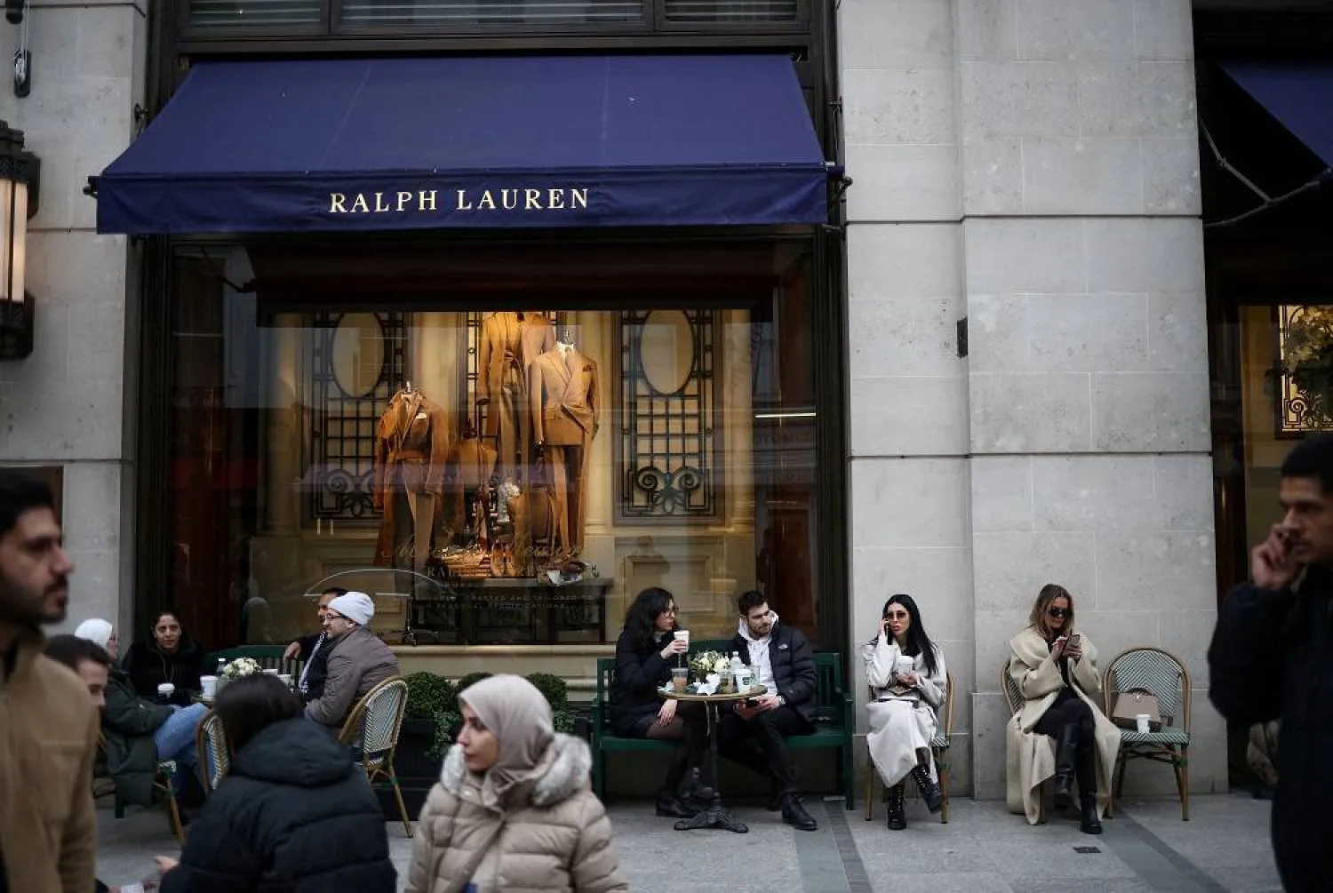 People sit outside a Ralph Lauren store on New Bond Street in London, Britain, March 11, 2023. (Reuters) 