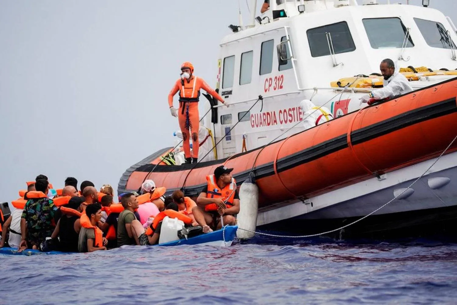 Members of Italian Guardia Costiera prepare to bring on board the migrants of a wooden boat near the island of Lampedusa, in the Mediterranean Sea, September 1, 2021. REUTERS/Juan Medina

