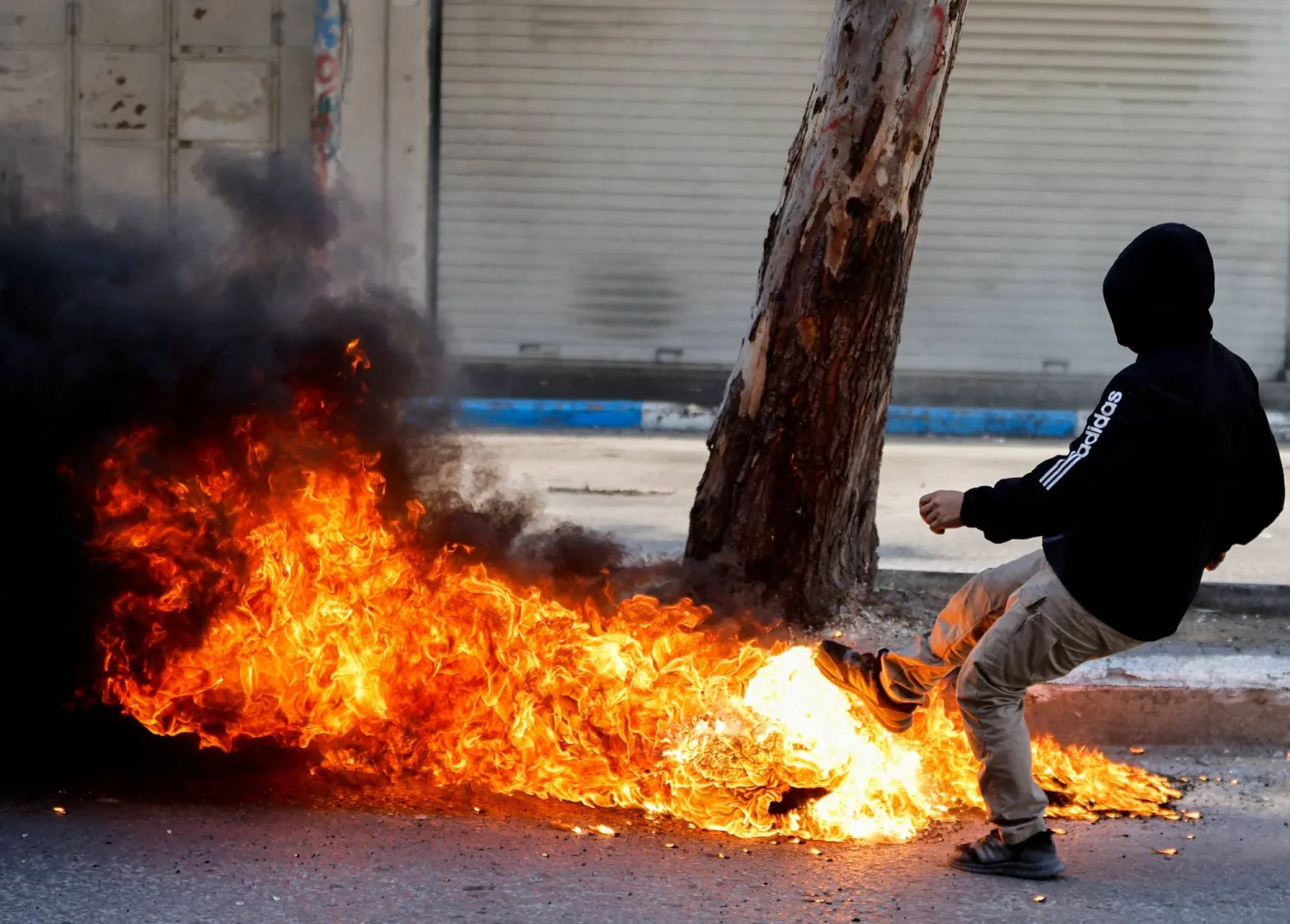 A Palestinian kicks a burning object during clashes between Palestinians and Israeli soldiers following the death of Palestinian prisoner Khader Adnan during a hunger strike in an Israeli jail, in Hebron in the Israeli-occupied West Bank May 2,2023. REUTERS/Mussa Issa Qawasm