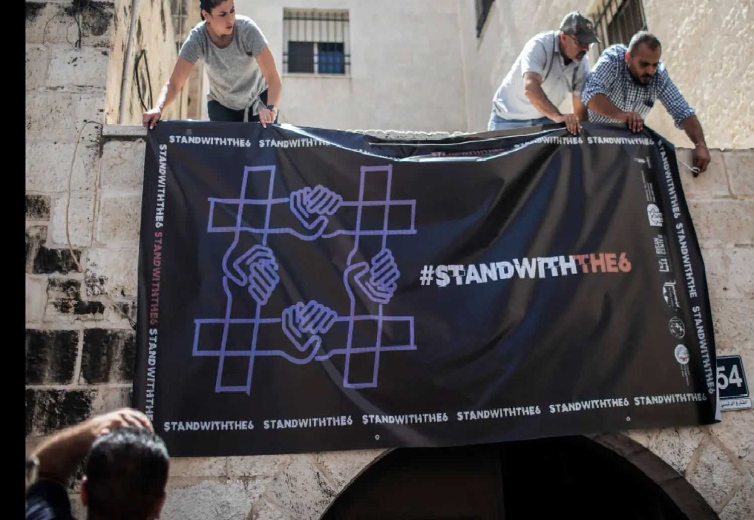 نشطاء يعلّقون لافتة تضامناً مع منظمات مجتمع مدني فلسطينية محظورة في أغسطس 2022 (د.ب.أ)