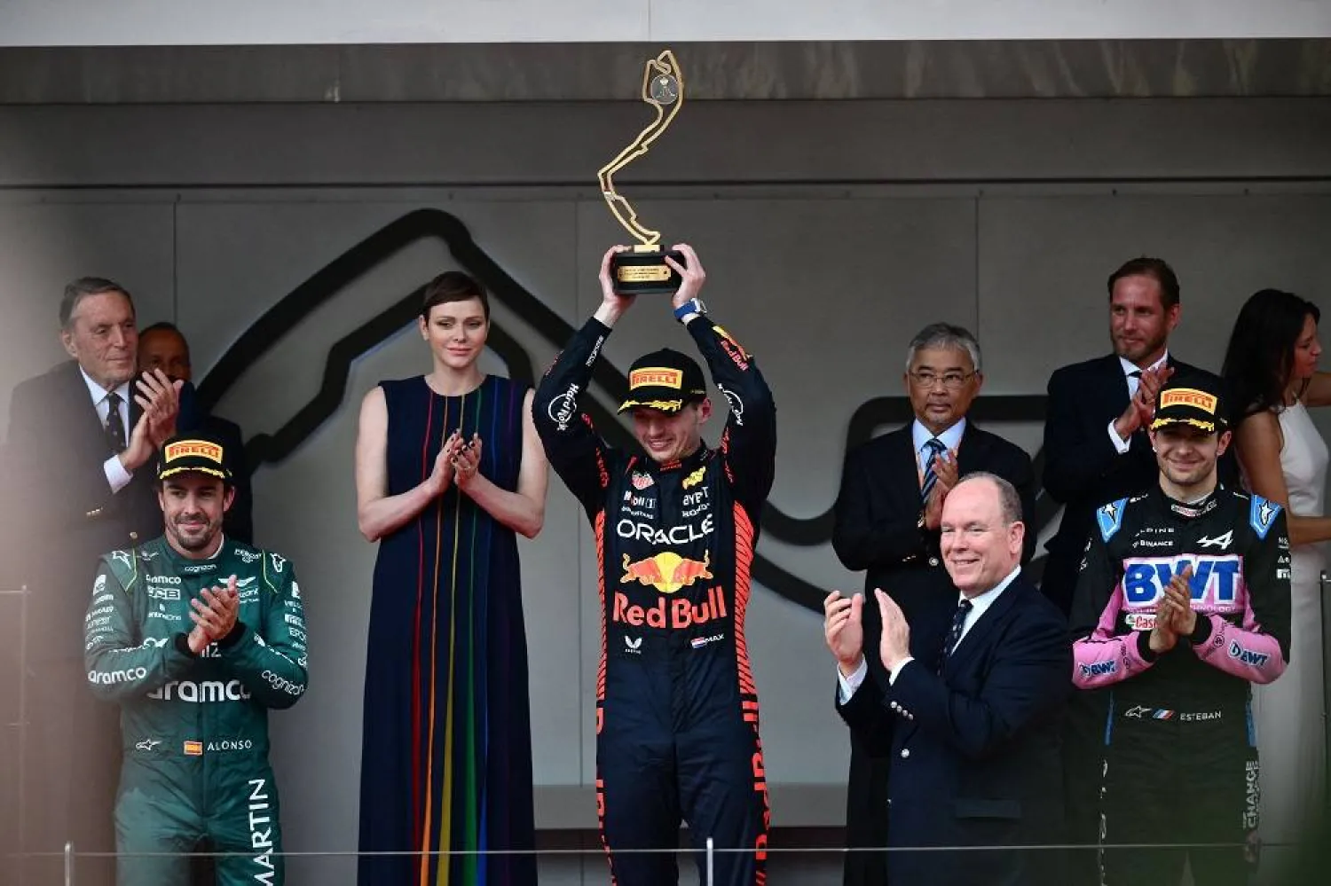 Winner Red Bull Racing's Dutch driver Max Verstappen (C) holds up his trophy, flanked by second-placed Aston Martin's Spanish driver Fernando Alonso (L), third-placed Alpine's French driver Esteban Ocon (R), Prince Albert II of Monaco (2nd R) and Princess Charlene of Monaco (2nd L) on the podium after the Formula One Monaco Grand Prix at the Monaco street circuit in Monaco, on May 28, 2023. (AFP) 