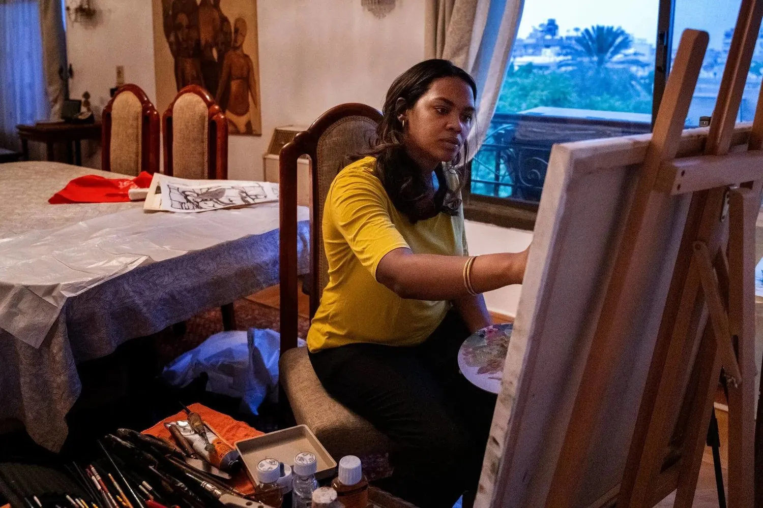Sudanlı sanatçı Dalya Abdul İlah Be`şer Kahire’deki yeni evinde resim yapıyor (The New York Times)