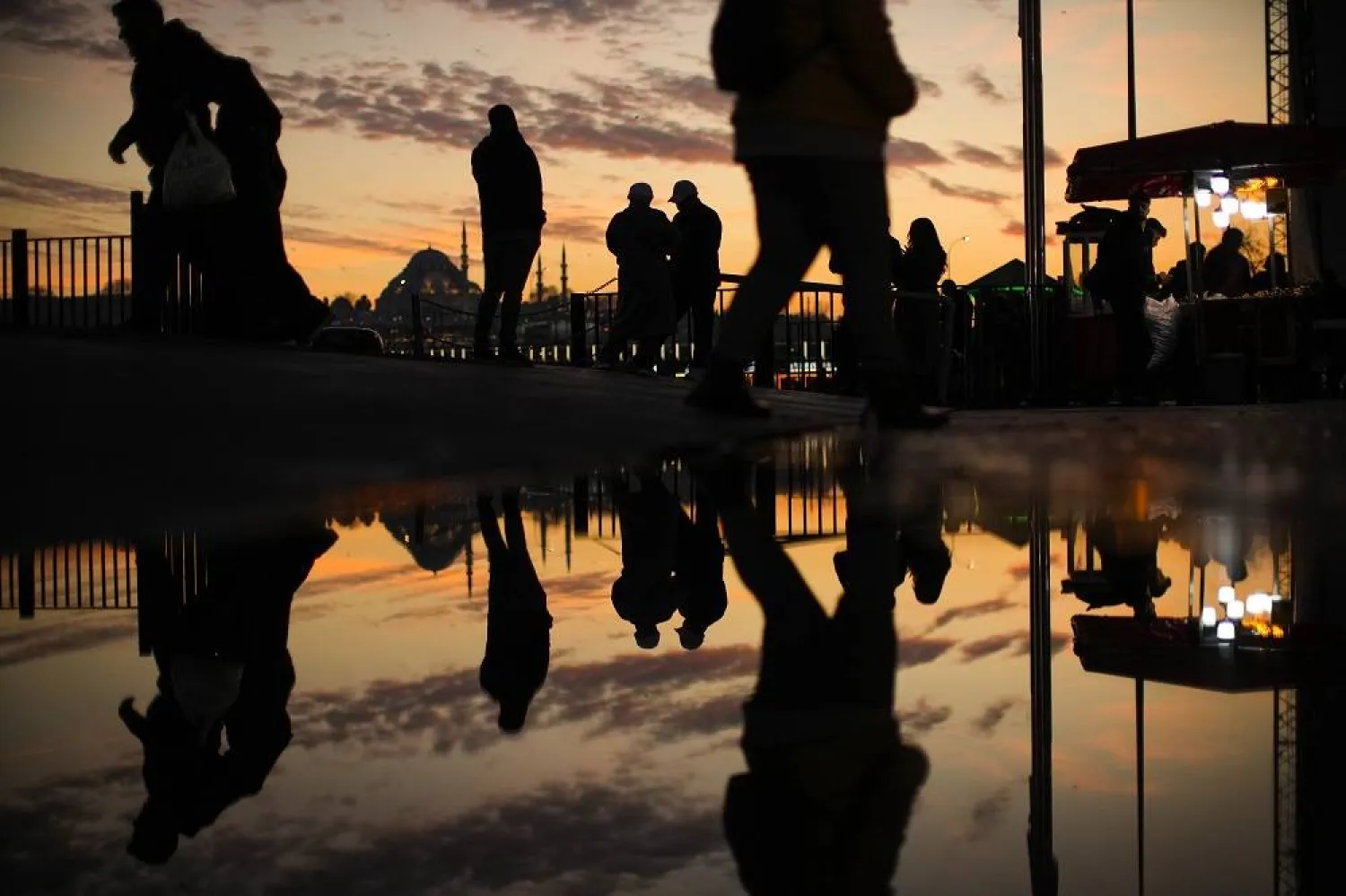 Pedestrians walk next to Karakoy ferry terminal as the sun sets behind Suleymaniye mosque, background, in Istanbul, Türkiye, Wednesday, Feb. 22, 2023. (AP) 