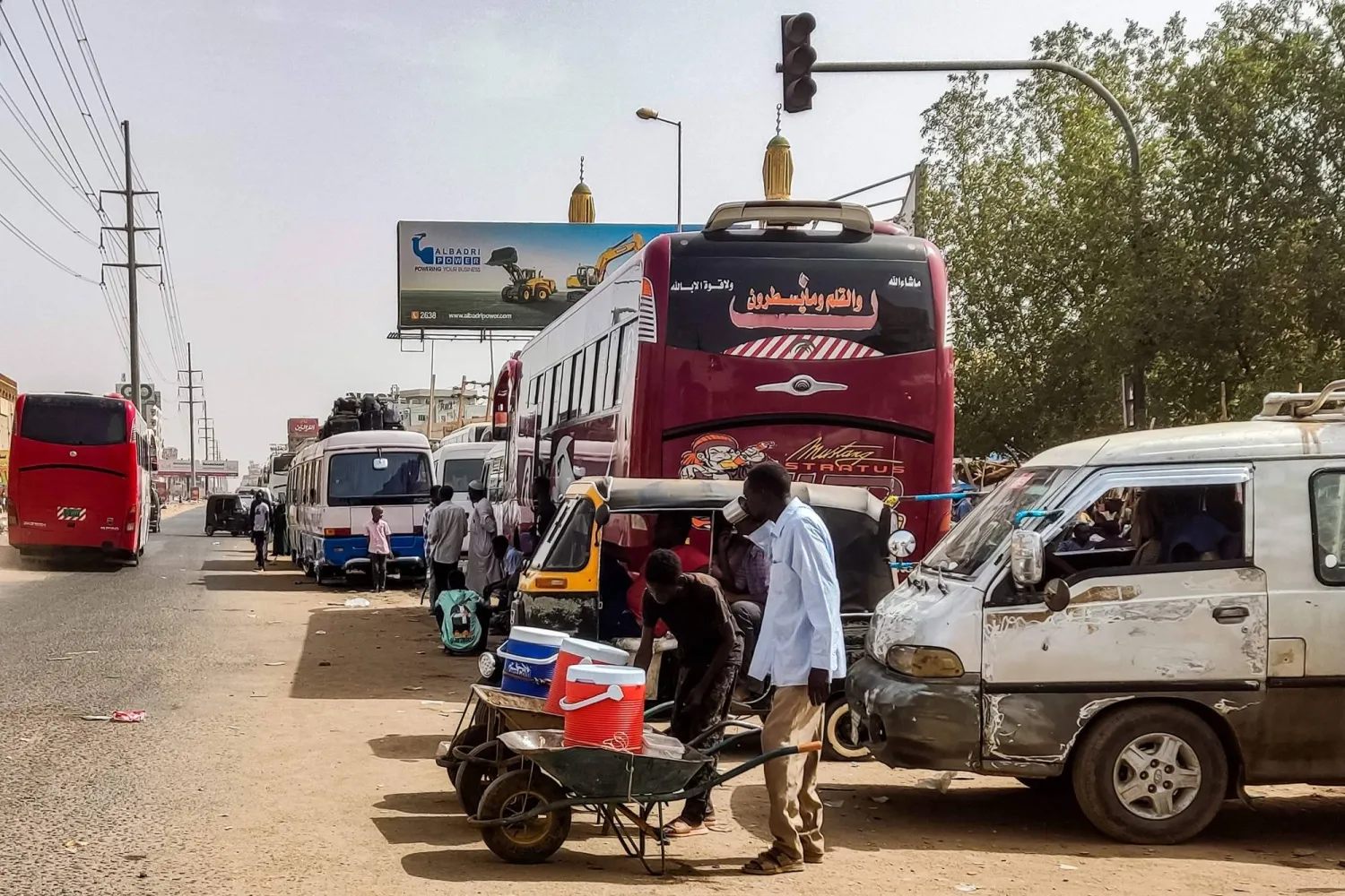 A man has a drink of water as buses wait for passengers fleeing violence to depart from al-Sittin (sixty) road in the south of Khartoum on May 30, 2023. (Photo by AFP)