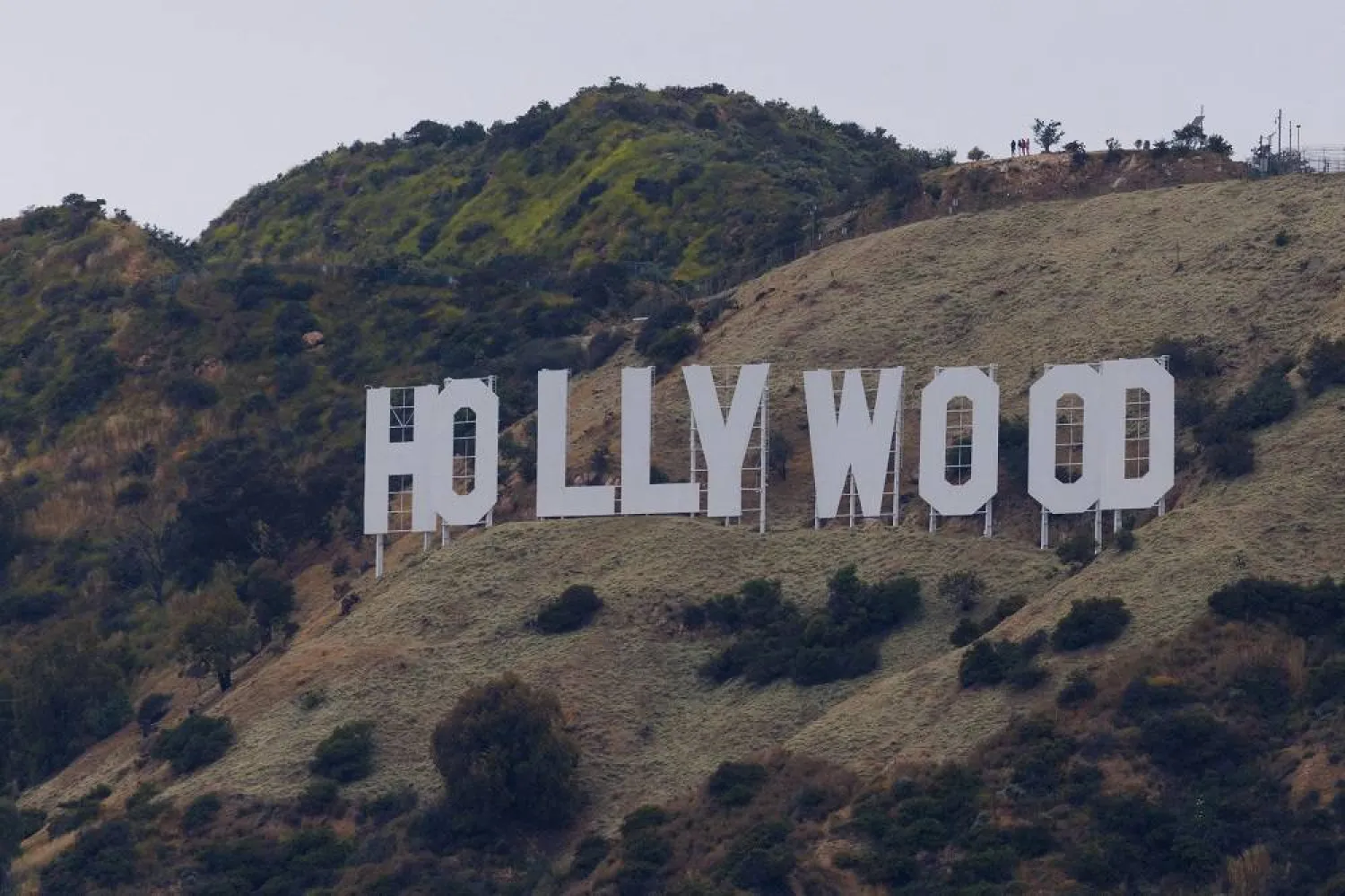 People stand above the Hollywood sign under a cloudy sky in Los Angeles, California, US, May 31, 2023. (Reuters) 