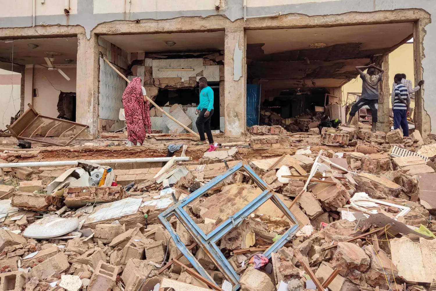 أشخاص يتفقدون اليوم الثلاثاء منزلاً في جنوب الخرطوم تحول إلى ركام بعد أن طاله القصف المدفعي مع استمرار الاشتباكات في السودان (أ.ف.ب)