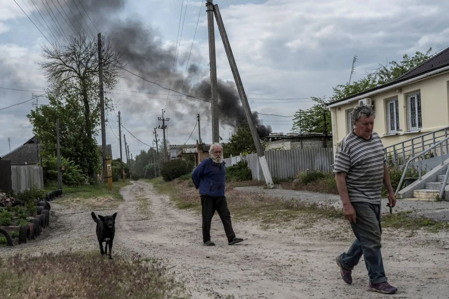 رجلان يسيران وسط ارتفاع أعمدة الدخان بسبب القصف في خاركيف (رويترز)