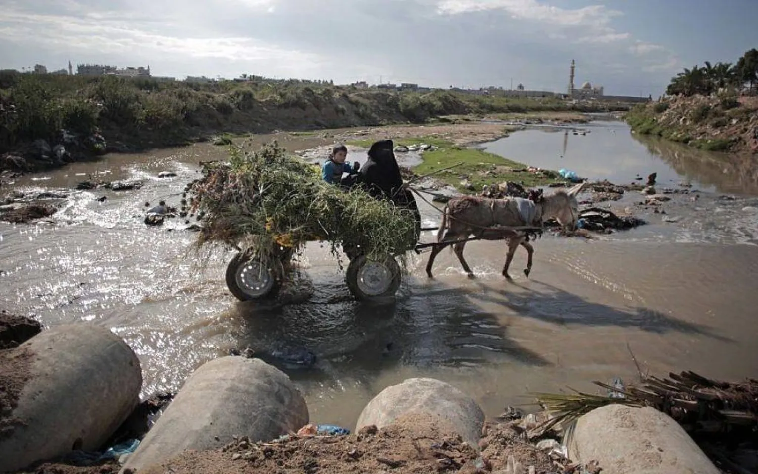 أشخاص يَعبرون فوق مياه صرف صحي بمحيط مدينة غزة في 13 أبريل 2016 (أ.ب)