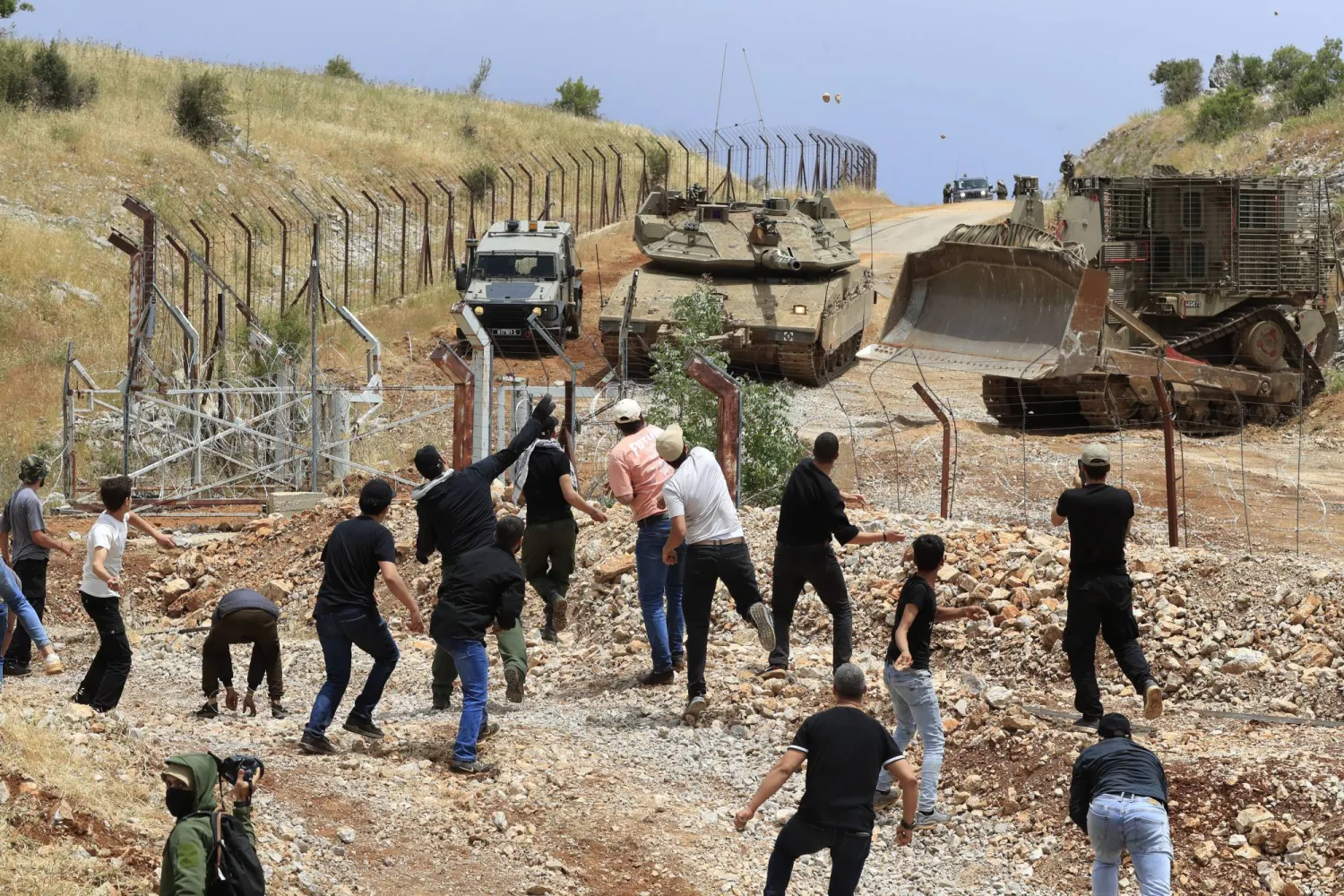 مواطنون يرمون الحجارة على قوة إسرائيلية عند أطراف بلدة كفر شوبا في جنوب لبنان أمس (أ.ب) 