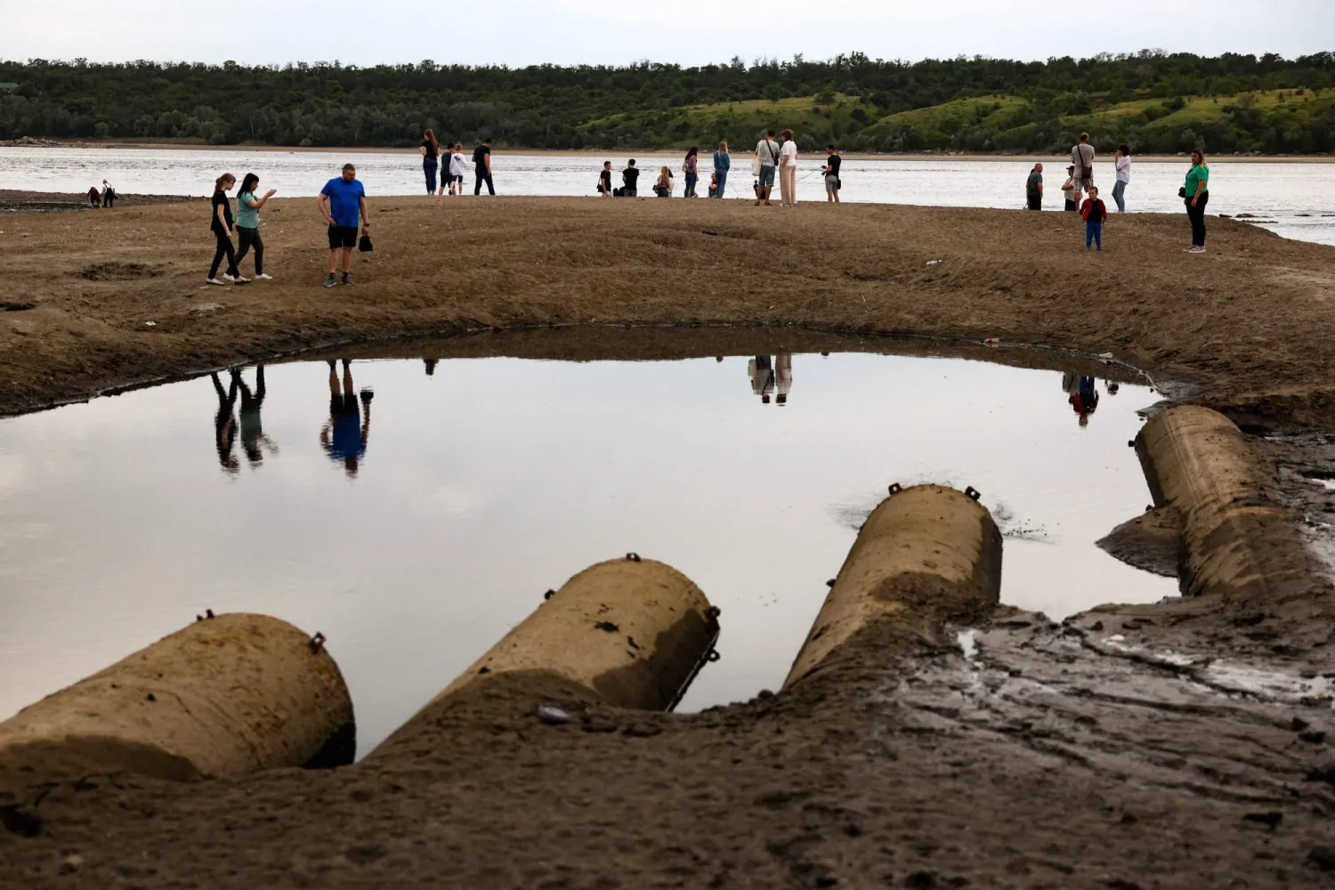 سكان من زابوريجيا يسيرون وسط الطين فوق نهر دنيبرو (أ.ف.ب)