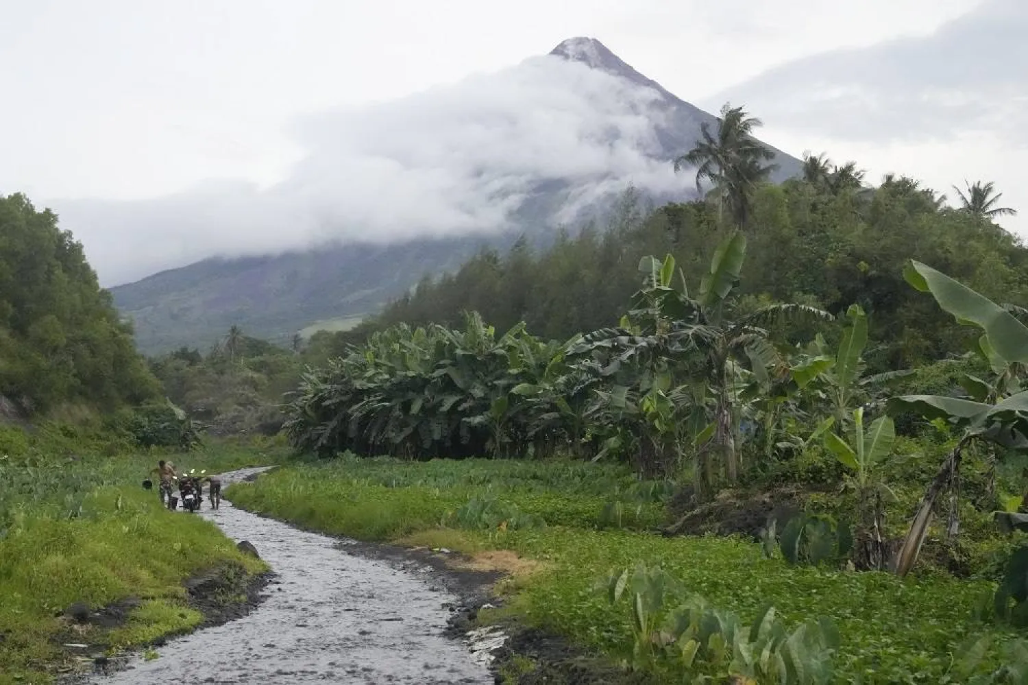 Men wash their motorcycles along a stream near Mayon volcano in Bonga, Albay province, northeastern Philippines, Saturday, June 10, 2023. (AP) 
