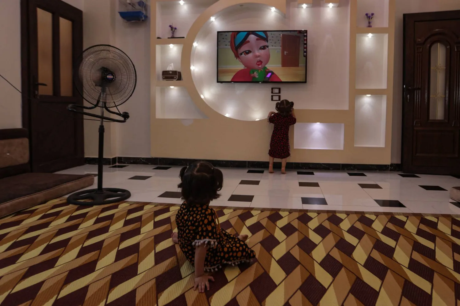 طفل يجلس لمشاهدة التلفزيون على سجادة مصنوعة من البلاستيك(أ ف ب)