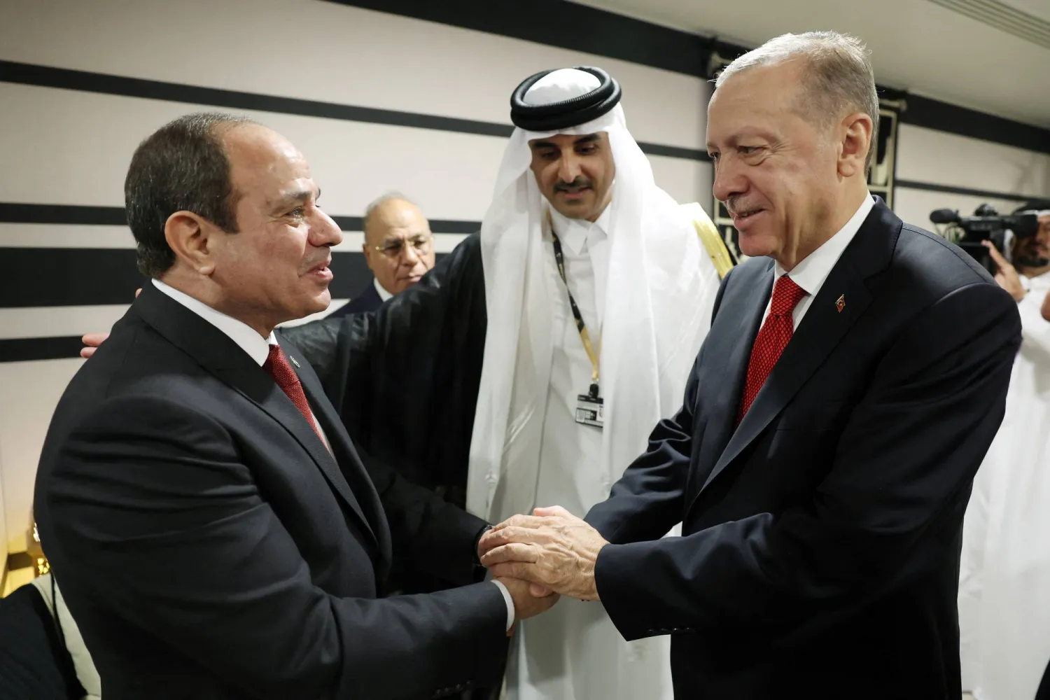 Egyptian President Abdel Fattah Sisi shakes hands with Turkish President Recep Tayyip Erdogan at the presence of the Emir of Qatar during World Cup 2022 in Doha (Reuters)