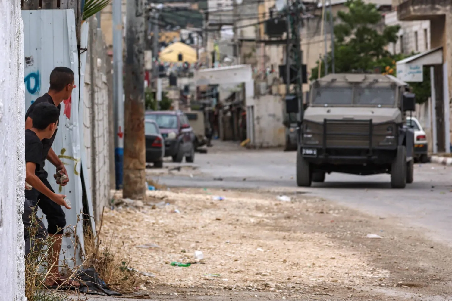 شبان فلسطينيون يلقون الحجارة على مركبات تابعة للجيش الإسرائيلي أثناء مداهمة إسرائيلية لمخيم بلاطة في ضواحي نابلس اليوم (أ.ف.ب)