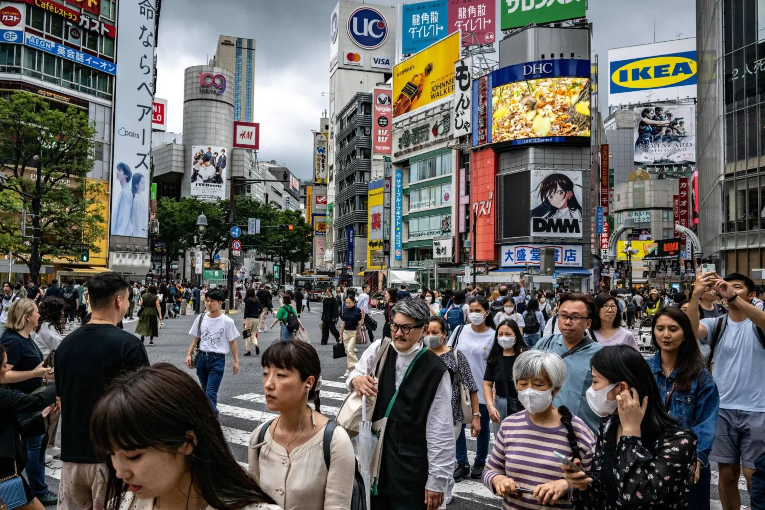 People walk across "Shibuya Crossing" in the Shibuya district of Tokyo on June 14, 2023. (Photo by Philip FONG / AFP)