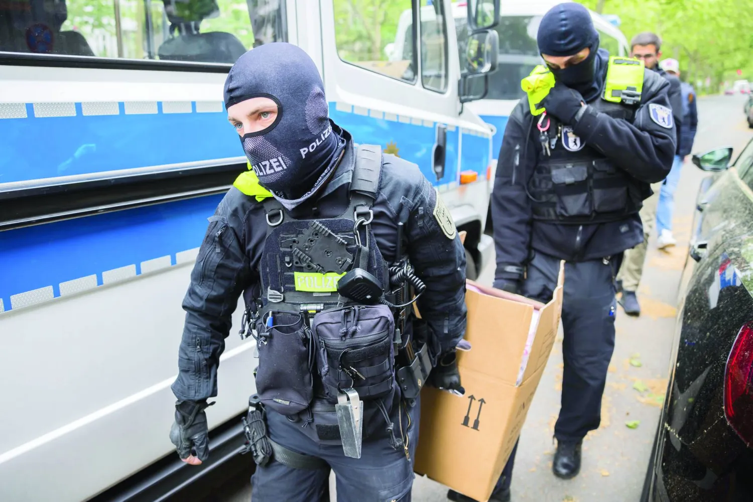 ضباط الشرطة يحملون صندوقاً من الورق المقوى إلى سيارة خلال مداهمة في برلين بألمانيا الأربعاء 24 مايو 2023 (د.ب.أ)