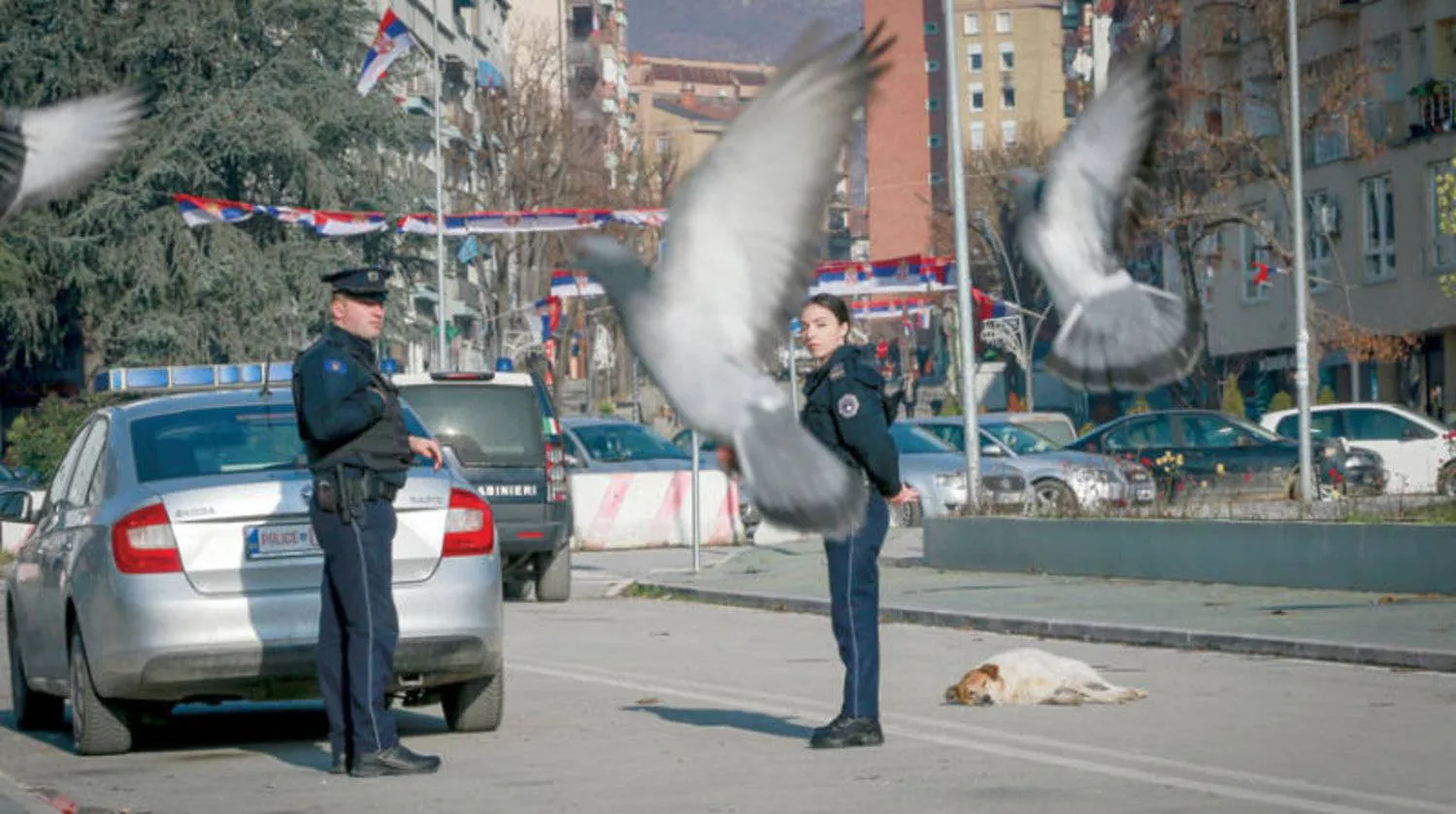شرطيان من كوسوفو يحرسان جسراً يفصل بين الجنوب الصربي والشمال الألباني في ميتروفيتشا (أ.ب)