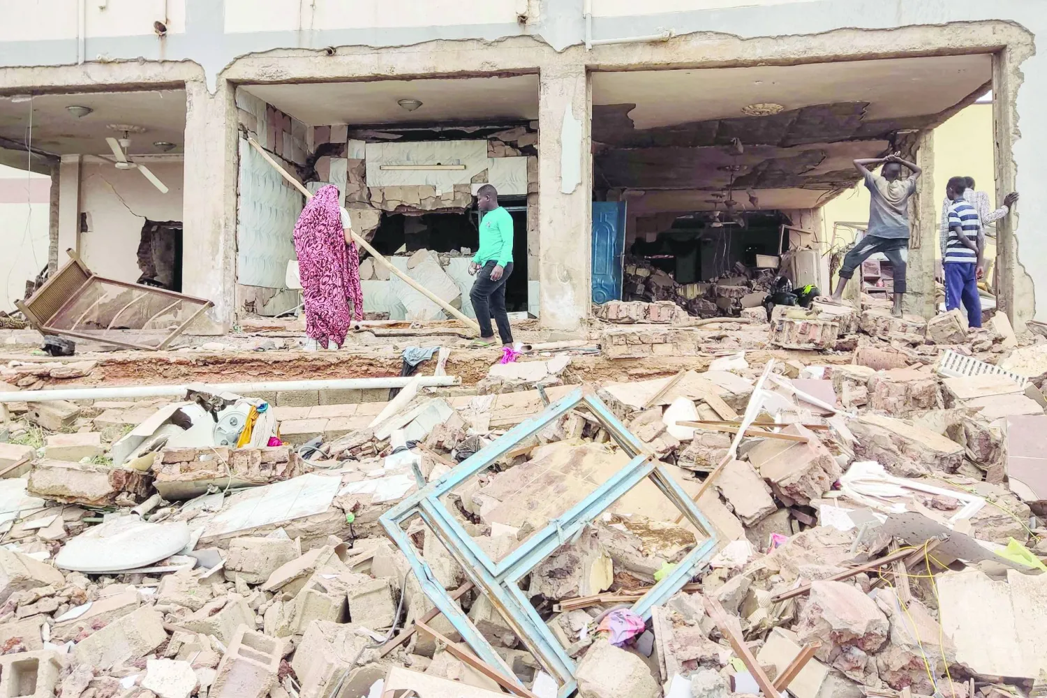 أشخاص يتفقدون منزلاً في جنوب الخرطوم تحوَّل إلى ركام بعد أن طاله القصف المدفعي مع استمرار الاشتباكات في السودان (أ.ف.ب)