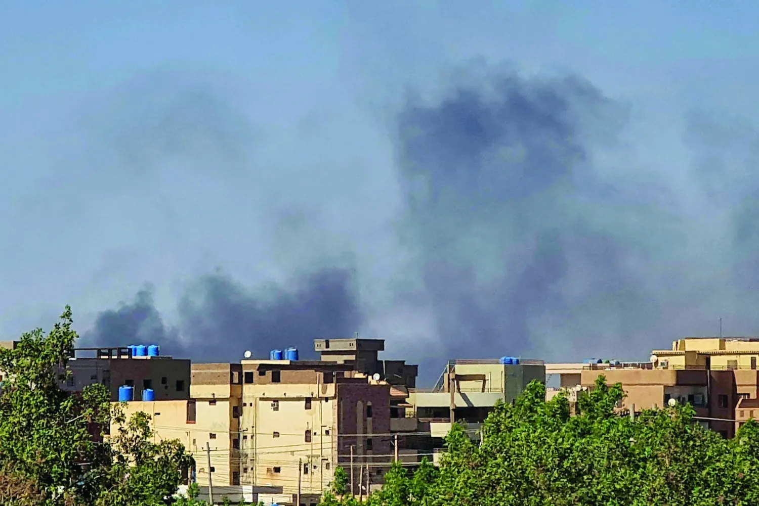 الدخان يتصاعد خلف المباني بأحد أحياء الخرطوم وسط استمرار الحرب في السودان (أ.ف.ب)