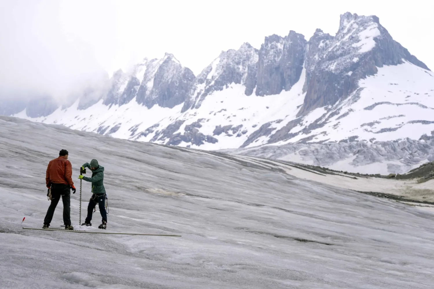 Team members of ETH (Swiss Federal Institute of Technology) glaciologist and head of the Swiss measurement network 'Glamos', Matthias Huss, drill holes into the Rhone Glacier to take measurements near Goms, Switzerland, Friday, June 16, 2023. (AP Photo/Matthias Schrader)