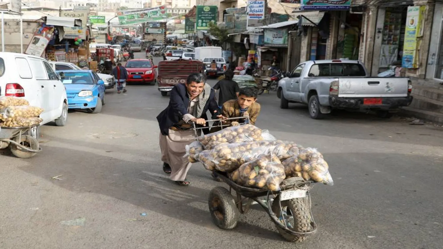  شابان يمنيان ينقلان عربة للبطاطس استعداداً لبيعها في إحدى أسواق العاصمة صنعاء (رويترز)