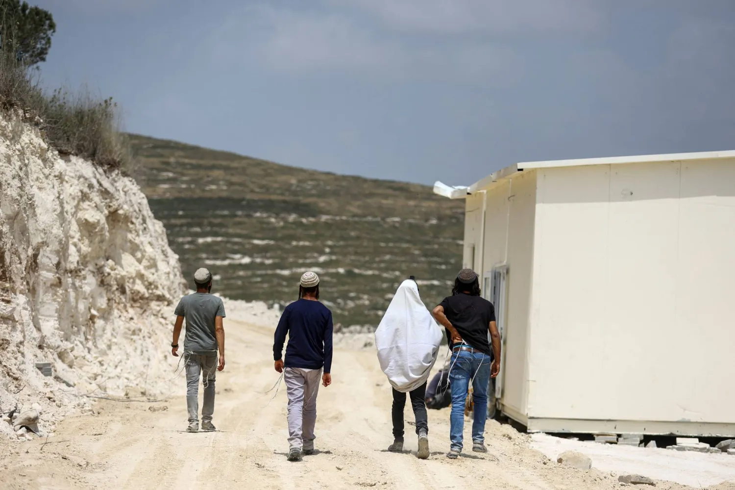 Israeli settlers walk past structures that were erected for a new Jewish seminary school, in the settler outpost of Homesh in the Israeli-occupied West Bank May 29, 2023 REUTERS/Ronen Zvulun