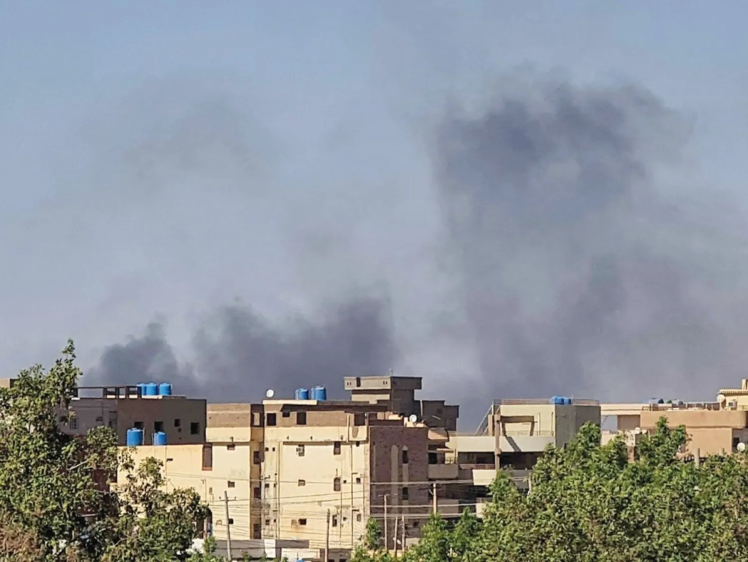 الدخان يتصاعد خلف المباني بأحد أحياء العاصمة السودانية (أ.ف.ب)