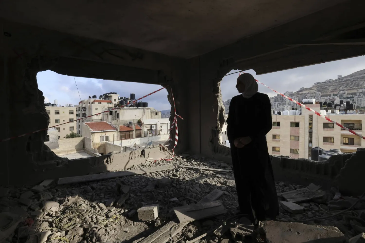 سيدة فلسطينية تقف في منزل دُمر بعد القصف الإسرائيلي في الضفة الغربية (إ.ب.أ)