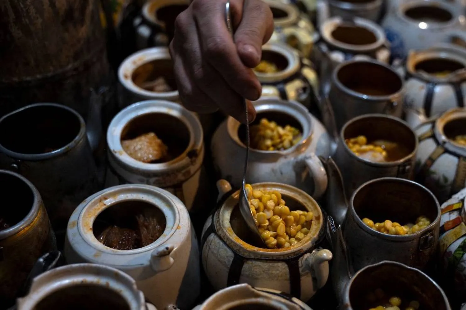 This photo taken on June 14, 2023 shows cook Kumail filling teapots with ingredients to prepare the traditional Chainaki lamb dish stew inside a restaurant at Koch-e Kafuroshi in Kabul. (AFP)