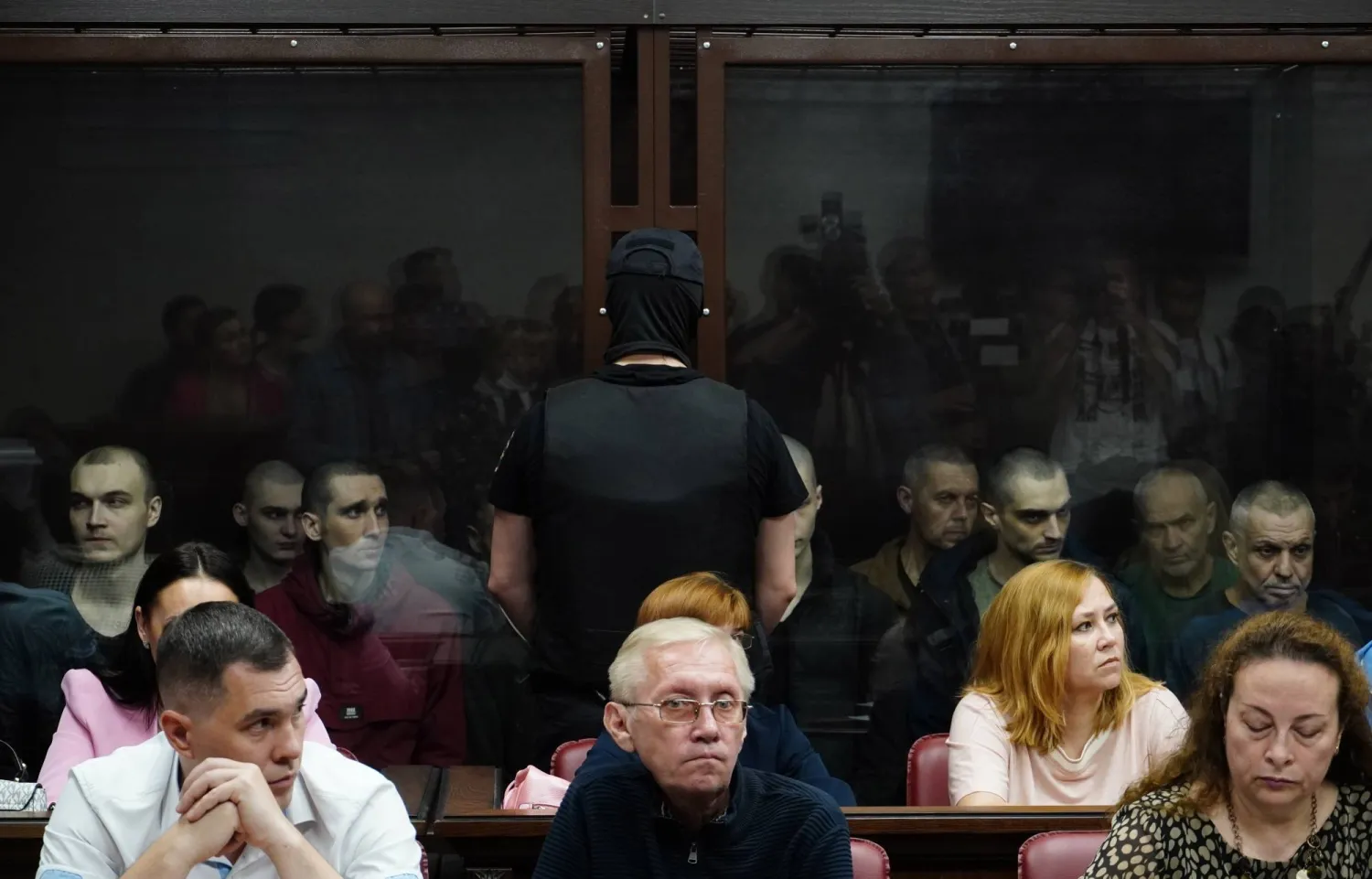 سجناء أوكرانيون داخل قفص الاتهام أثناء محاكمتهم في روسيا بتهمة الانتماء لمنظمة إرهابية في 14 يونيو 2023 (إي بي إيه)
