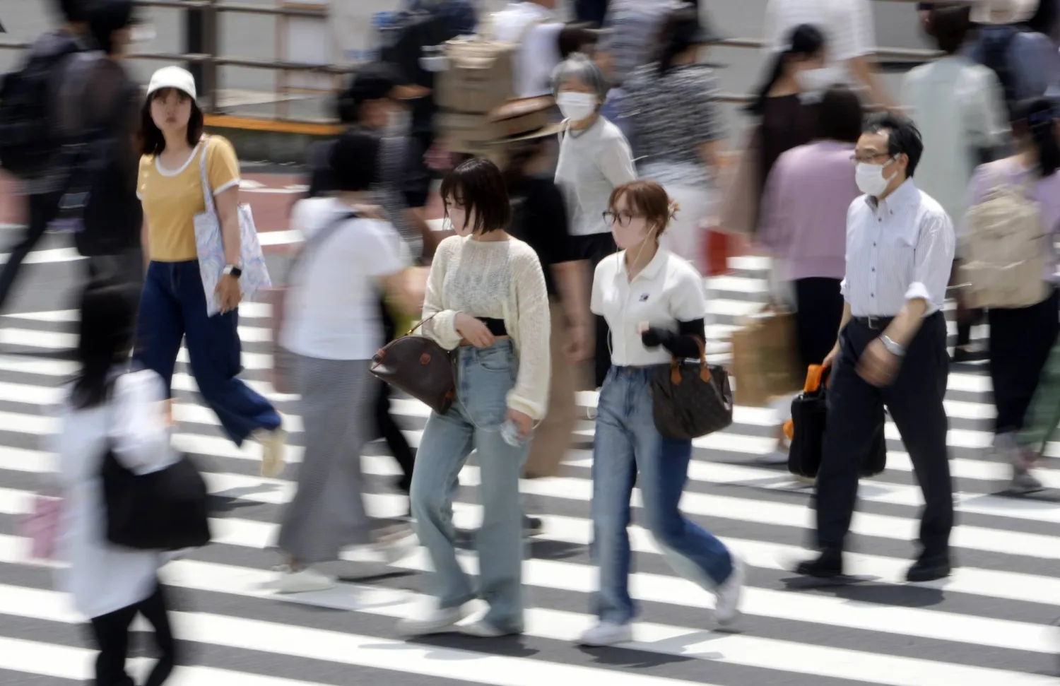 مشاة يعبرون الشارع في الضاحية المالية وسط العاصمة اليابانية طوكيو... بينما يؤكد البنك المركزي أن الاقتصاد يتحرك في اتجاه صعودي (إ.ب.أ)