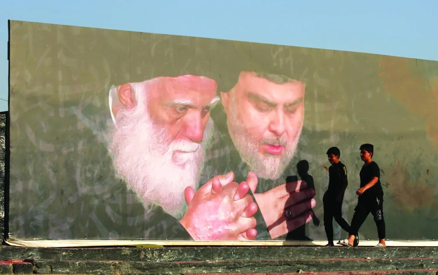 Bağdat'ın doğusundaki Sadr şehrinde asılı Mukteda es-Sadr ve babasının posteri. (EPA-Arşiv)