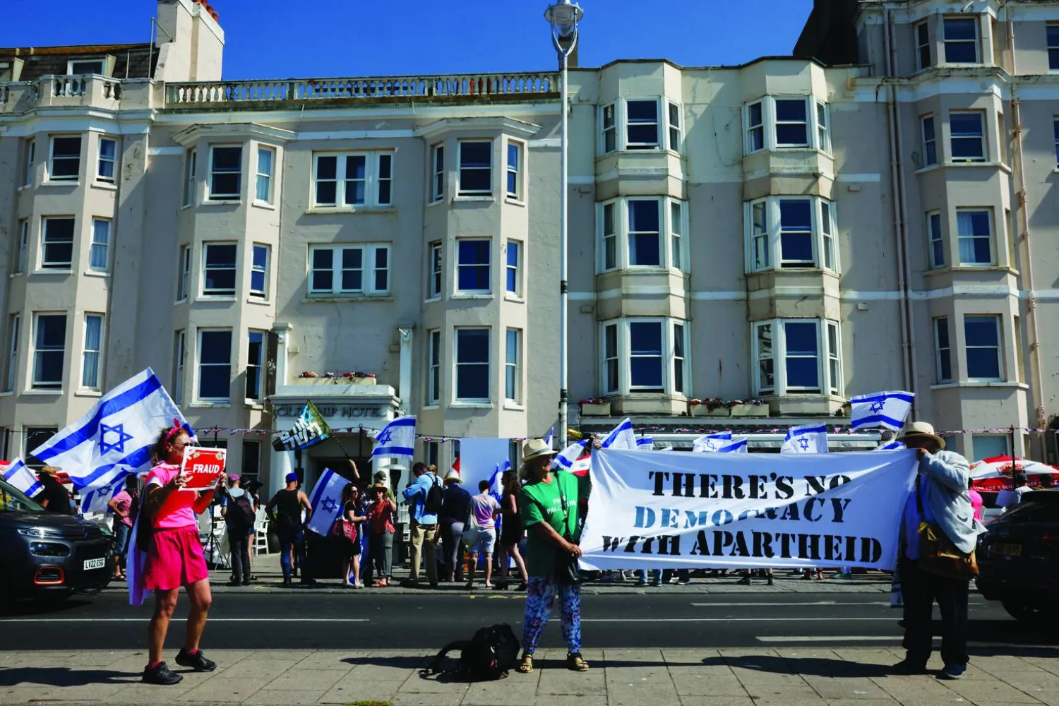 
متظاهرون خارج فندق «أولد شيب» في برايتون حيث يدلي أرنون ميلتشين بشهادته (رويترز)