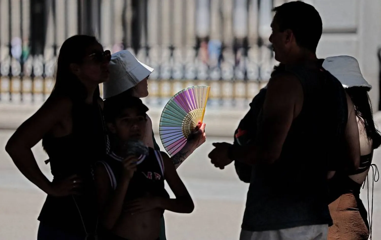 Tourists protect themselves from the sun as they are visiting the Royal Palace in Madrid city center under very high temperatures, on June 26, 2023. (AFP) 