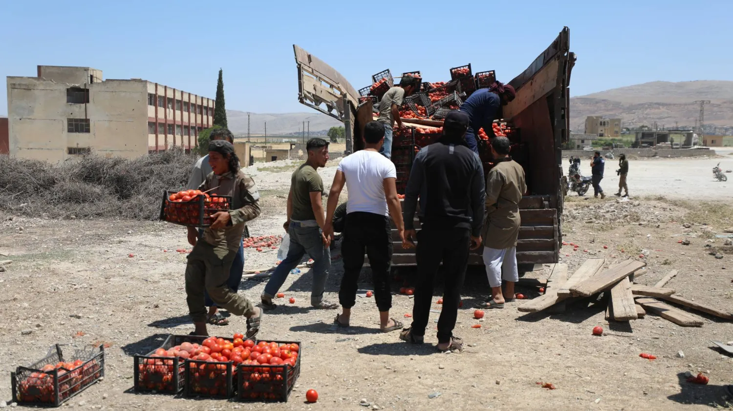 مواطنون بجانب شاحنة تضررت جراء الغارات الروسية على جسر الشغور بريف إدلب يوم الأحد (إ.ب.أ)