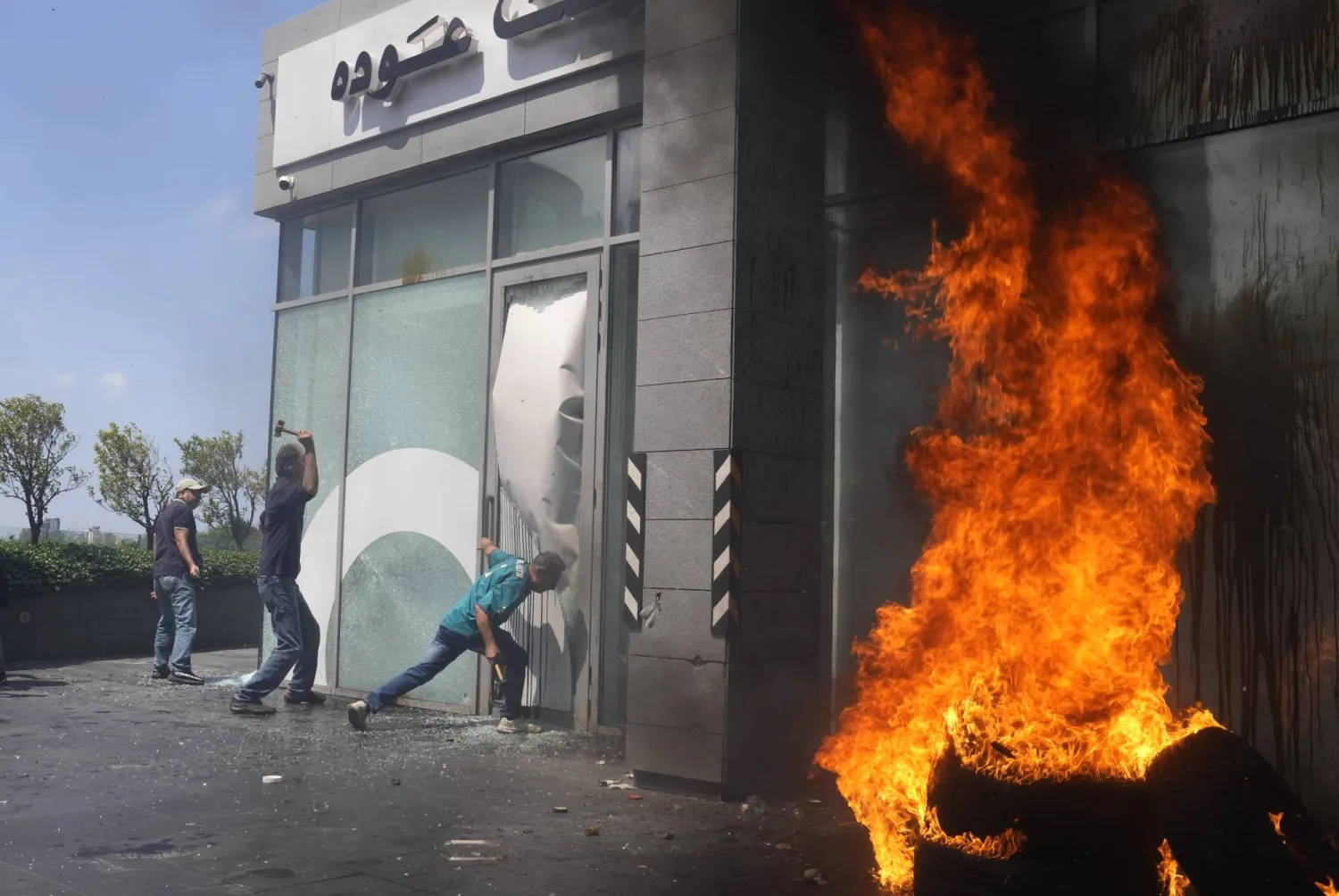FILE - Protesters smash windows and burn tires at Bank Audi during a protest demanding the release of depositors' trapped savings, in Beirut, Lebanon, Thursday, June 15, 2023. (AP Photo/Hussein Malla, File)