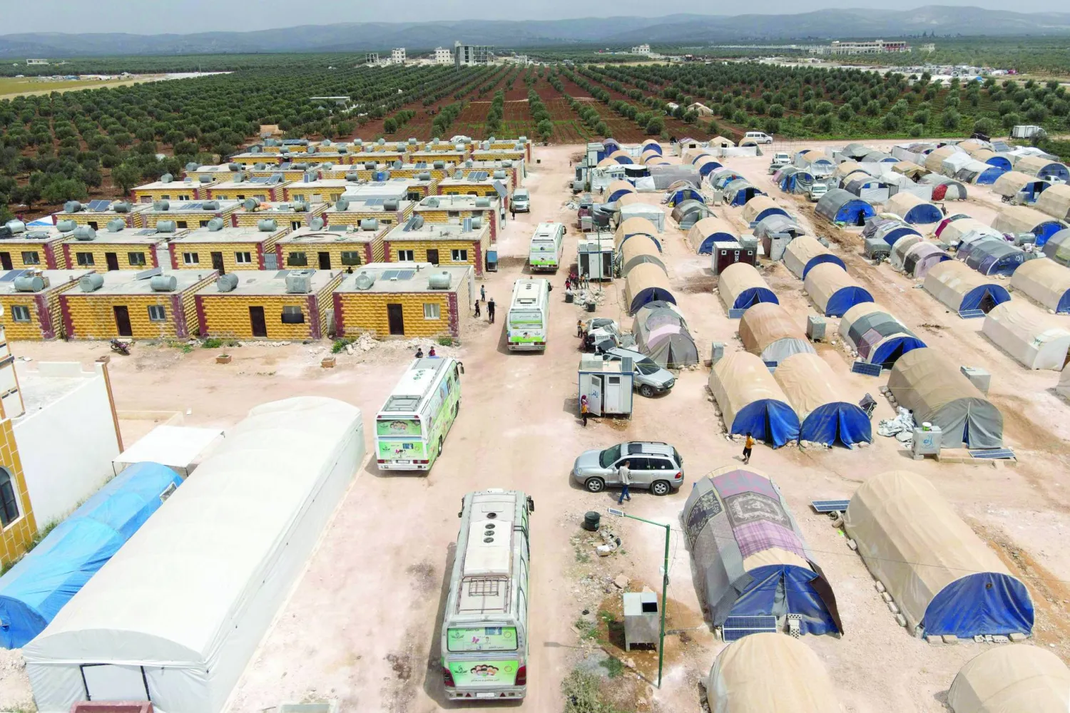 Buses turned into travelling classrooms pull into at a displacement camp in Jindayris in the opposition-held northwestern Syrian province of Aleppo on May 23, 2023, following a devastating earthquake more than three months ago. (Photo by Rami al SAYED / AFP)