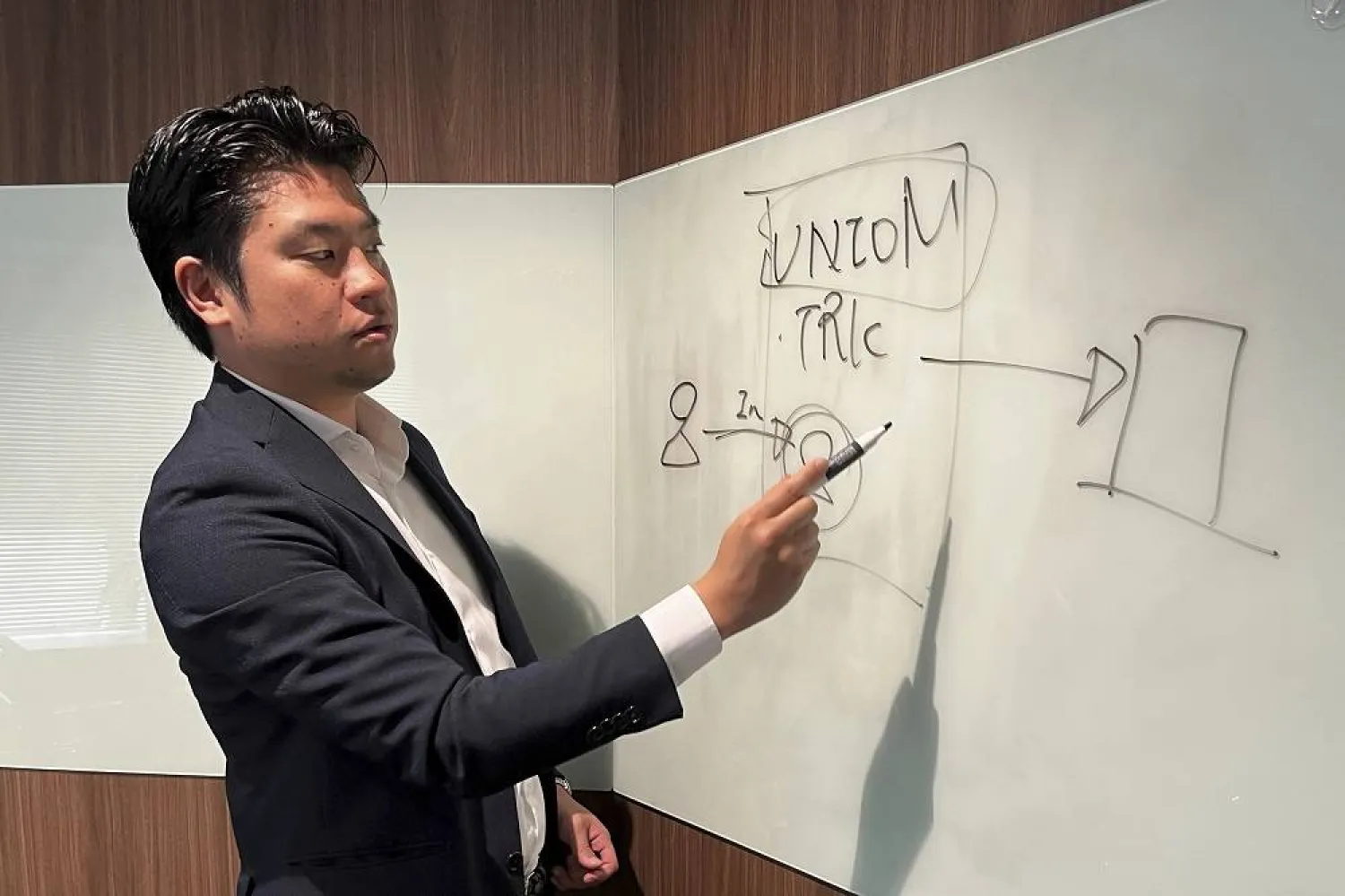 Yoshihito Hasegawa, who heads Tokyo-based TRK that runs a job-quitting service called Guardian, shows a diagram to explain what his service does at his office in Tokyo on June 21, 2023. (AP) 