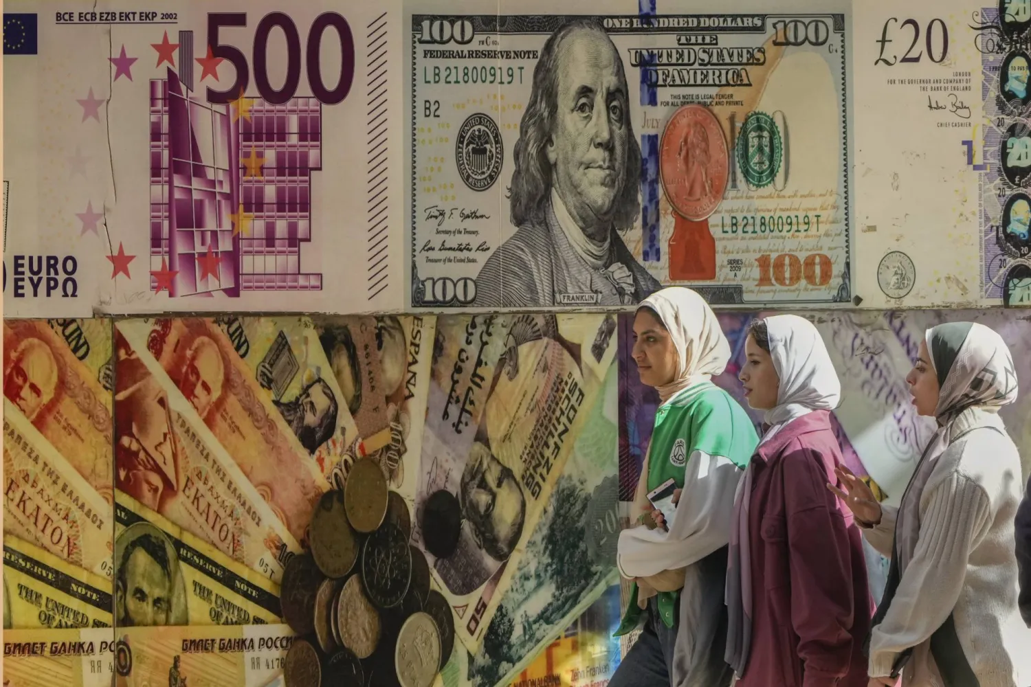 فتيات مصريات يعبرن (الخميس) أمام إحدى شركات الصرافة في القاهرة (أ.ب)