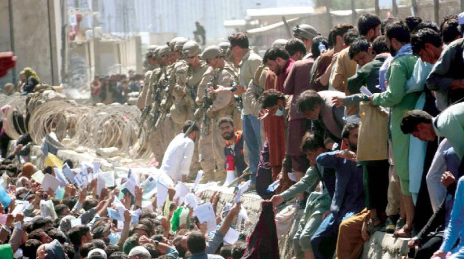 أفغان يحاولون عرض مستنداتهم على القوات الأجنبية في مطار كابل خلال عملية الانسحاب من أفغانستان في 26 أغسطس 2021 (إ.ب.أ)