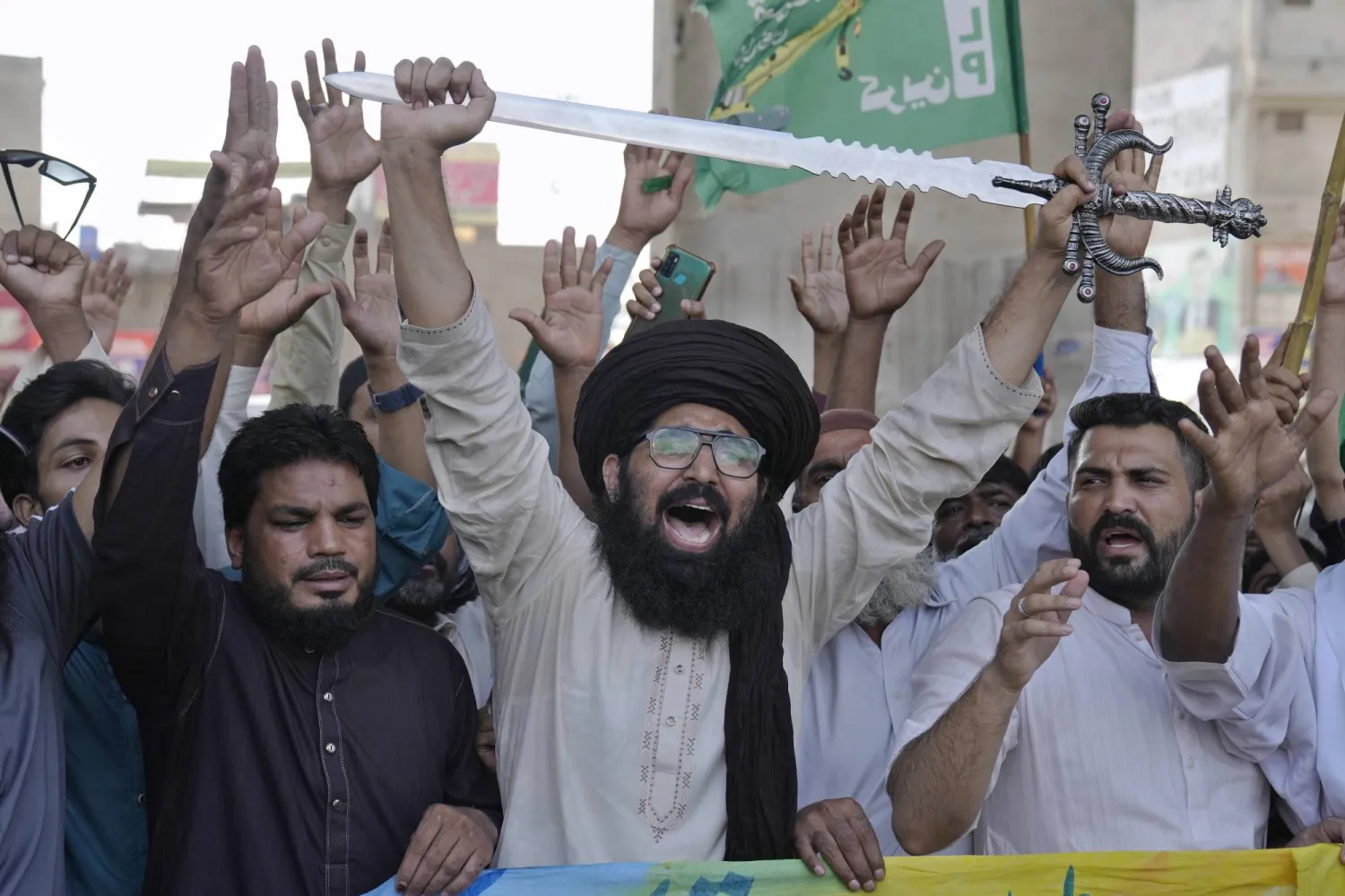 أحد مناصري تحريك «لبيك باكستان» يحمل السيف بينما يردد مع آخرين شعارات خلال مظاهرة ضد تدنيس كتاب الإسلام المقدس (القرآن) في السويد في لاهور الأحد (أ.ب)