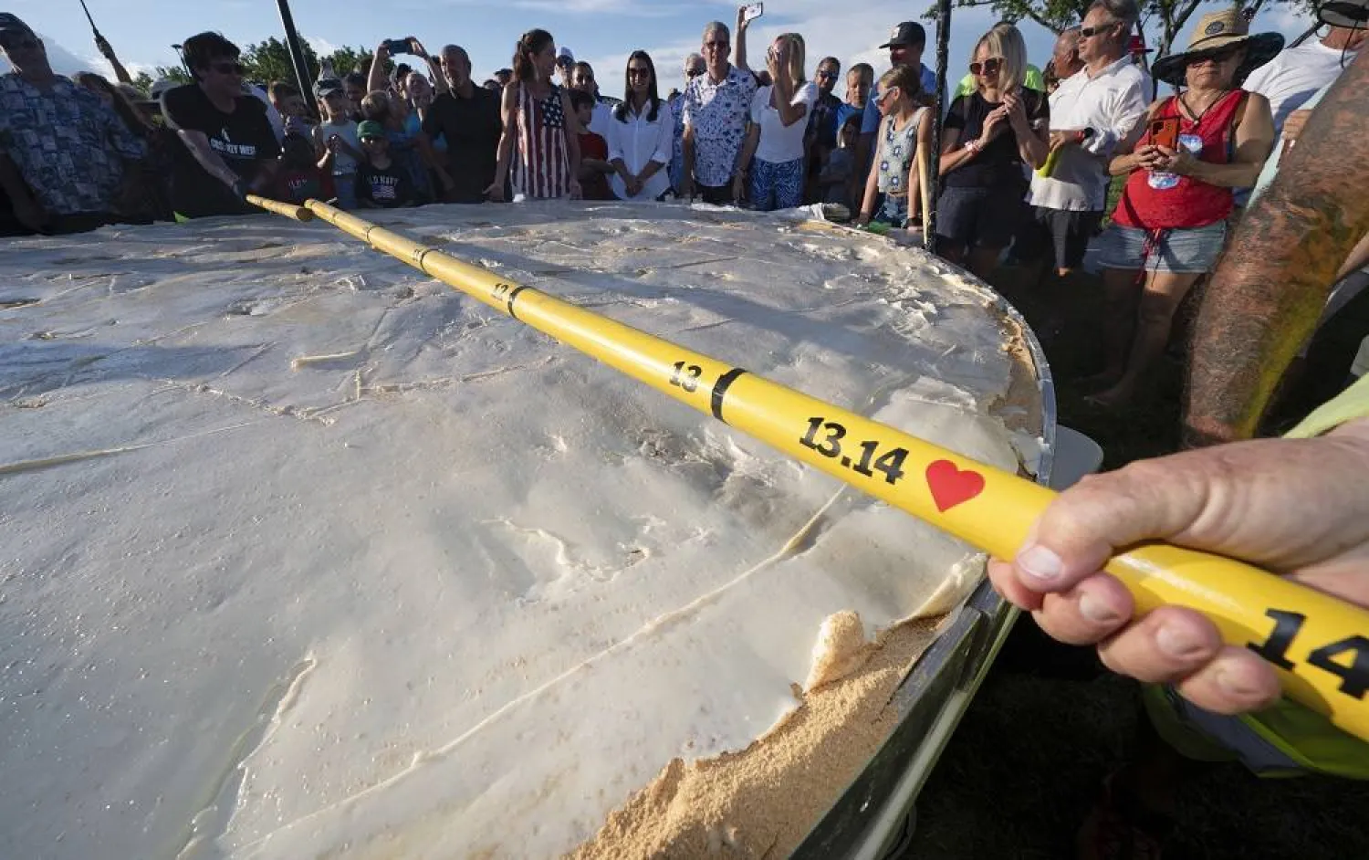 In this photo provided by the Florida Keys News Bureau, a measuring stick confirms the diameter of a gargantuan Key lime pie created for a 200th Florida Keys birthday celebration Monday, July 3, 2023, on Big Pine Key, Fla. (AP)