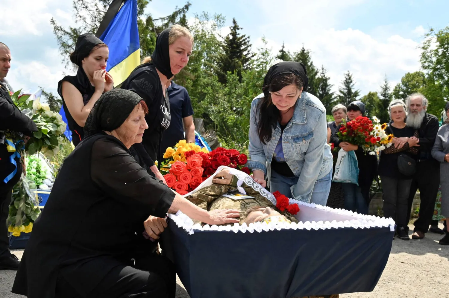 صورة في 29 يونيو 2023 لأقارب في حزن خلال مراسم جنازة في قرية تسيركوني بمنطقة خاركيف للمقاتل الأوكراني أولكسندر ستريابكو الذي قُتل بالقرب من باخموت (أ.ف.ب)