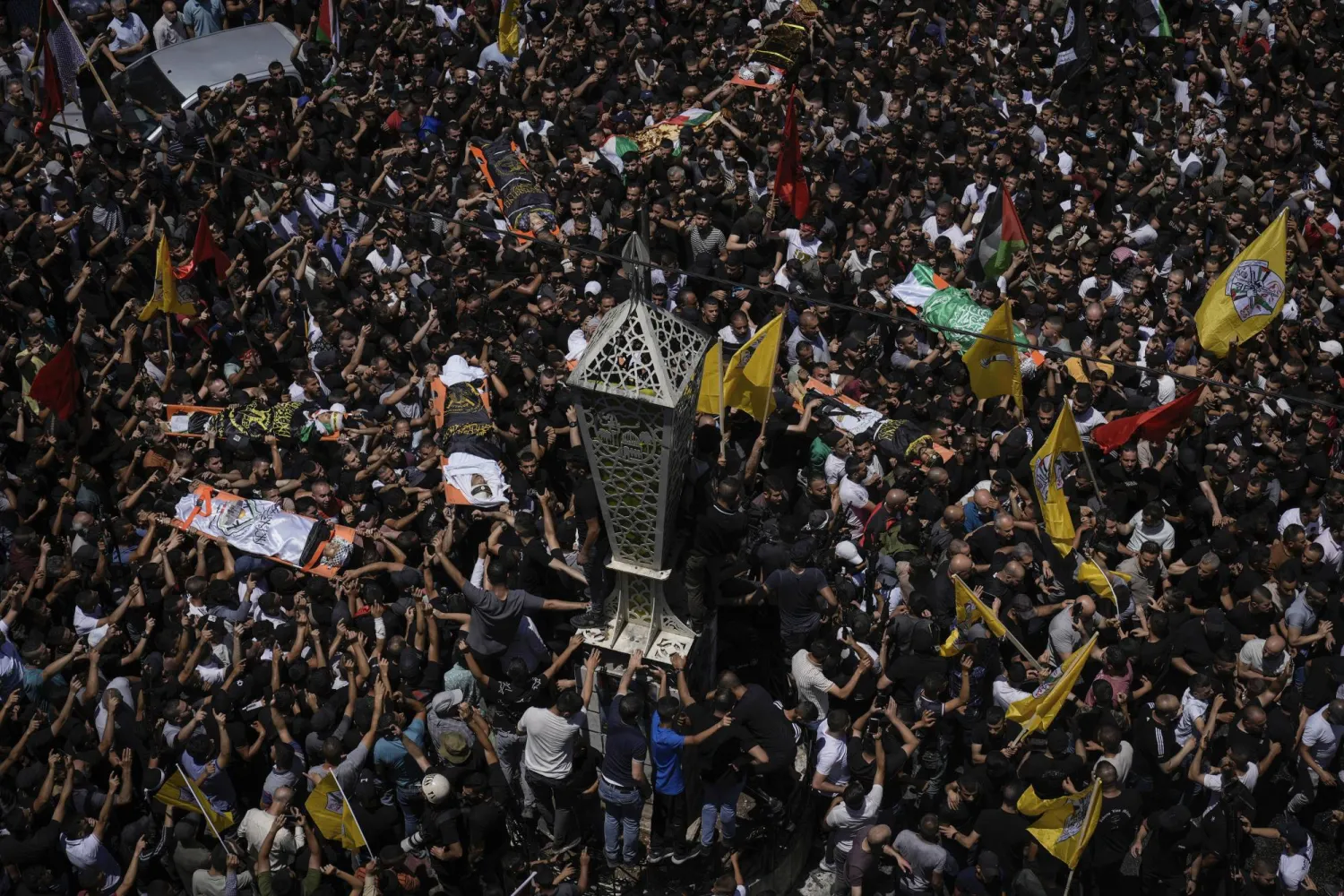 جثامين فلسطينيين بعضها ملفوف بأعلام «الجهاد» و«حماس» خلال جنازتهم في مخيم جنين الأربعاء (أ.ب)