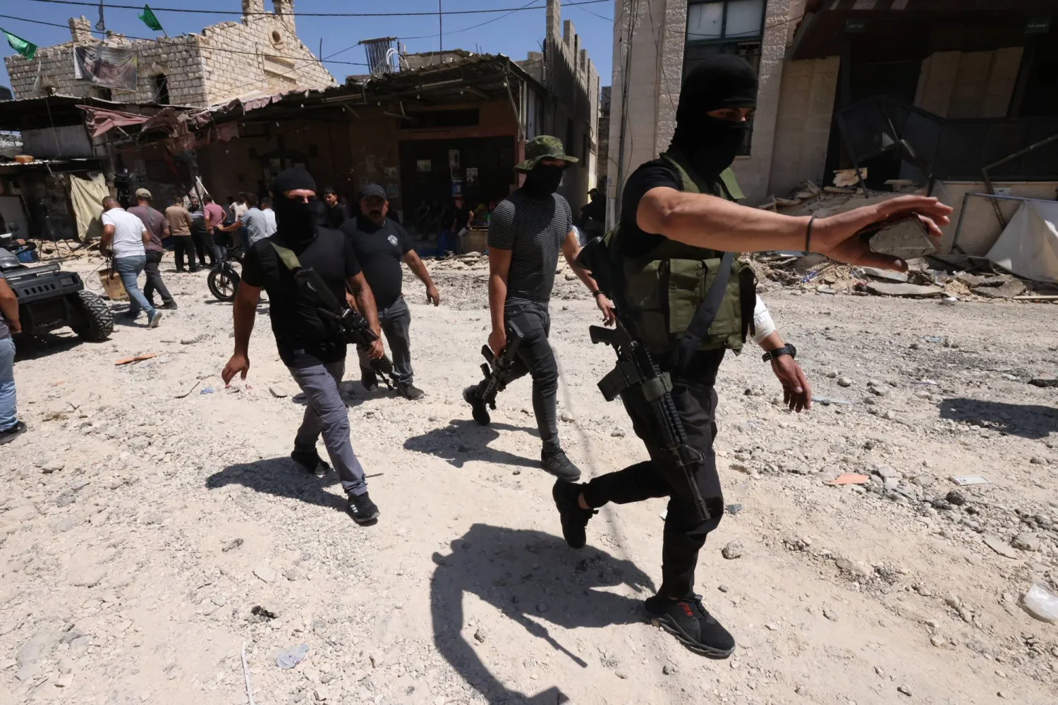 مسلحون فلسطينيون في شارع مدمر بمدينة جنين الأربعاء (إ.ب.أ)