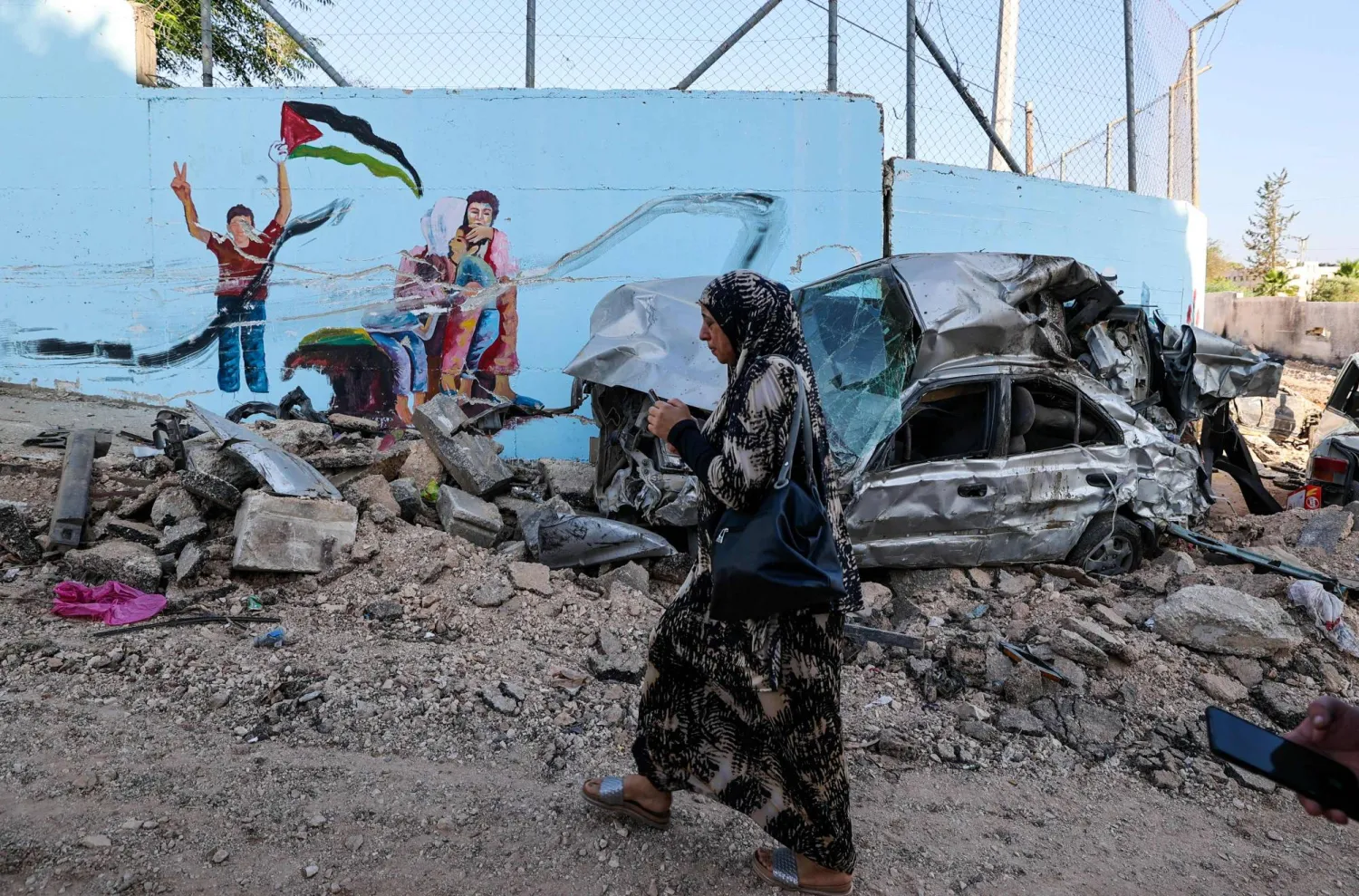 امرأة تسير بين الحطام في أحد شوارع مدينة جنين بالضفة الغربية بعد إعلان الجيش الإسرائيلي انتهاء عملية عسكرية استمرت يومين (أ.ف.ب)