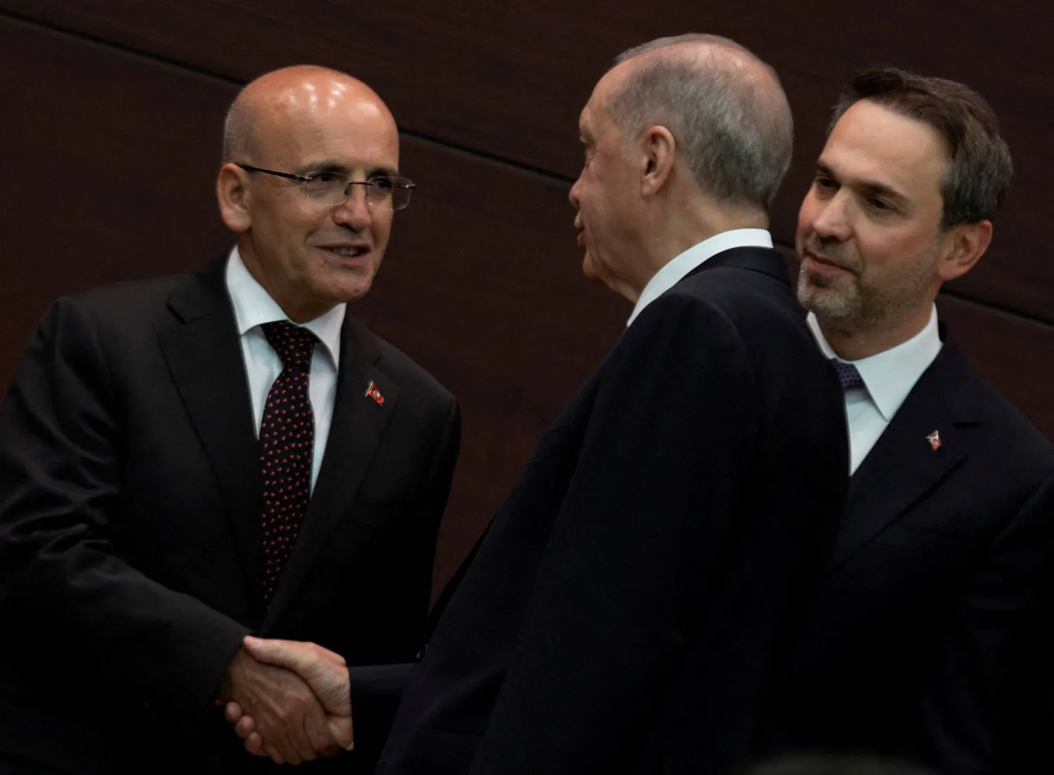 وزير المالية مصافحاً إردوغان خلال إعلان أعضاء الحكومة مطلع الشهر الماضي (رويترز)